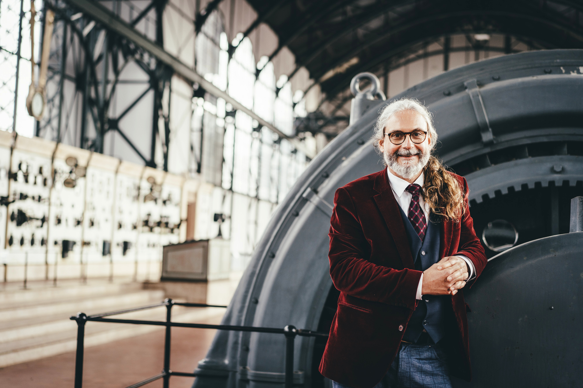 Mann steht lächelnd im Industriemuseum vor einem Ausstellungstück.