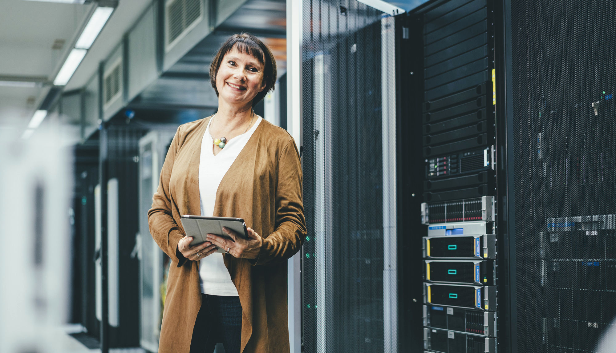Frau steht lächelnd im IT-Rechenzentrum.
