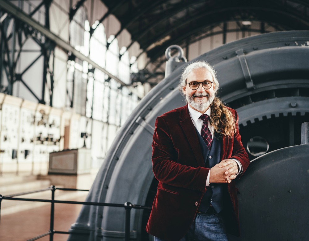 Mann steht lächelnd im Industriemuseum vor einem Ausstellungstück.