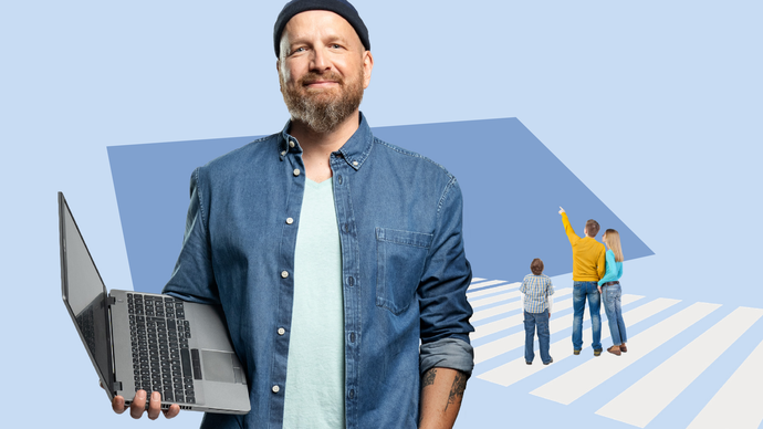 IT-Mitarbeiter steht mit Laptop in der Hand vor blauem Hintergrund.
